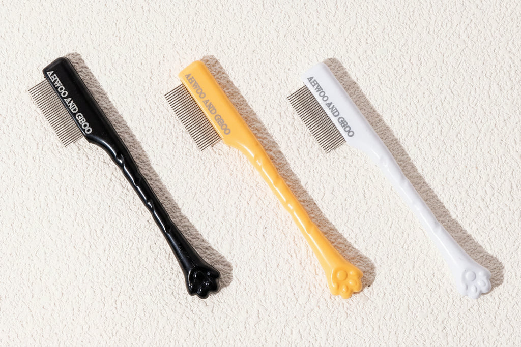 Pet grooming tools including a comb and brush on a textured surface 